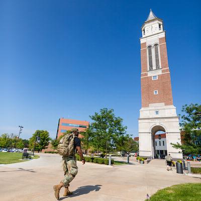 Man in army uniform walks toward Elliott Tower